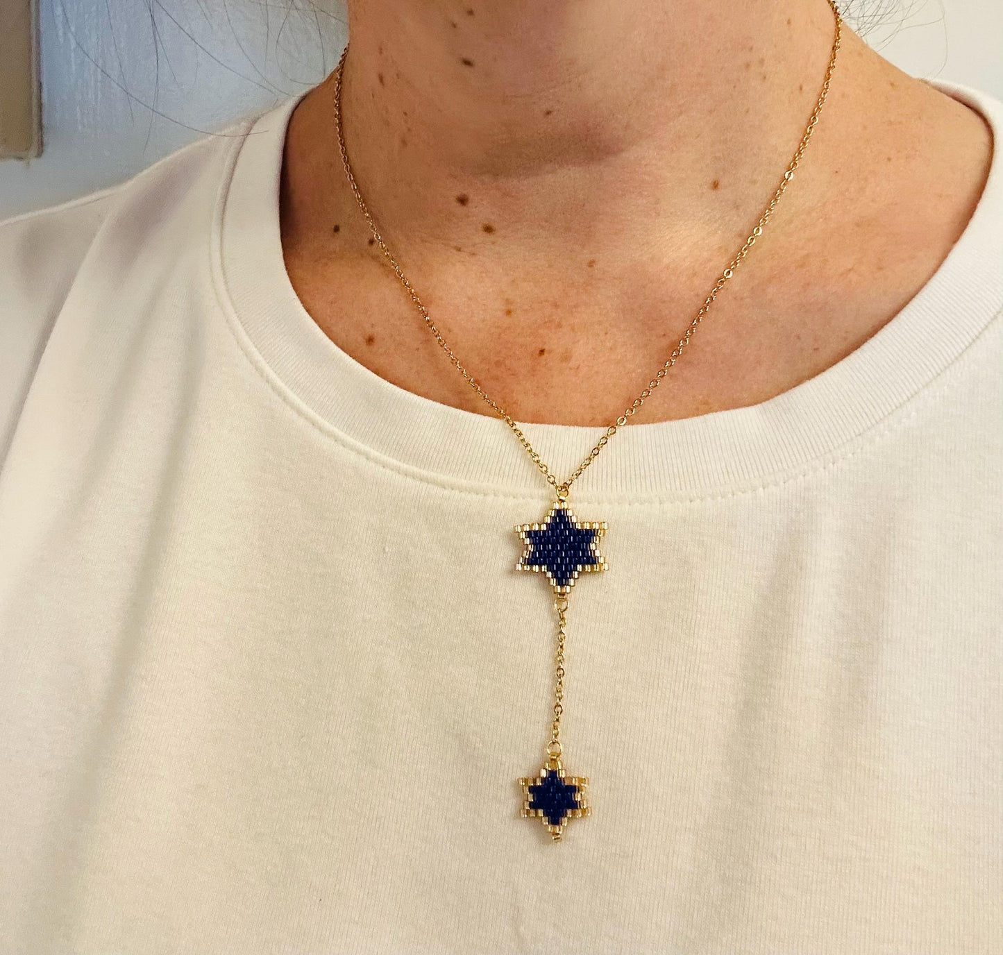 Close-up of Jewish beaded necklace with Double Star of David design on model frontal in blue